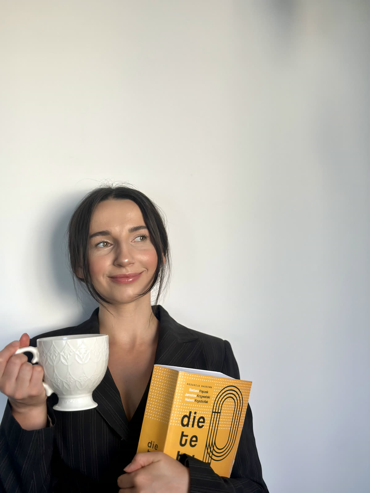 Katarzyna Biernat z kubkiem kawy i książką o dietetyce